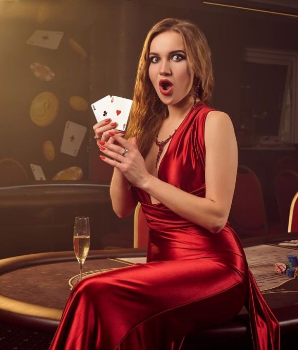 showy-blond-woman-long-red-satin-dress-with-two-aces-her-hands-is-looking-wondered-posing-sitting-poker-table-luxury-casino-passion-cards-chips-alcohol-win-gambling-it-is